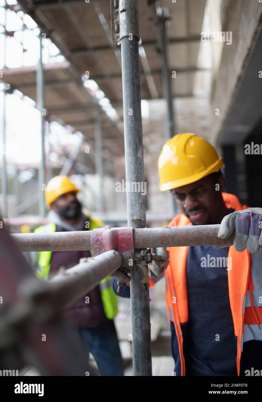 Montaggio di ponteggi maschio in cantiere Foto Stock