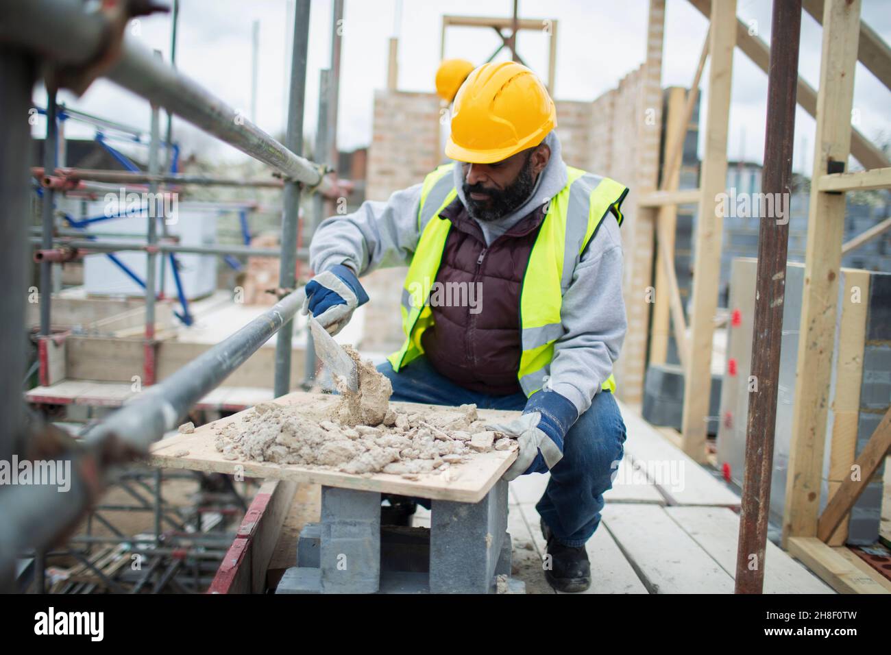 Lavoratore di costruzione maschile che mescola calcestruzzo in cantiere Foto Stock