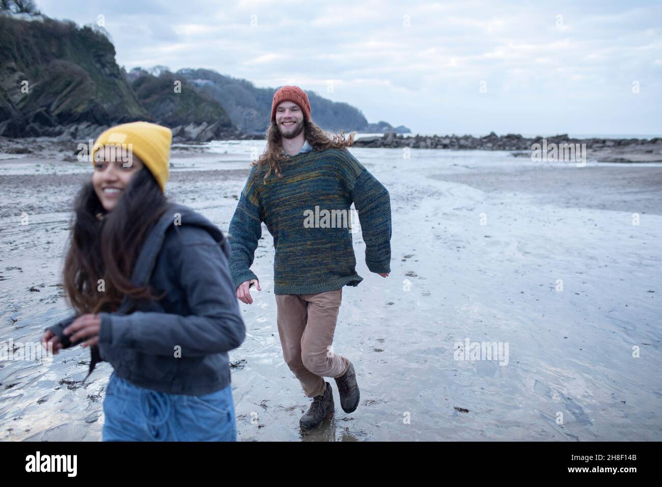 Felice giovane coppia che corre su spiaggia di sabbia bagnata Foto Stock