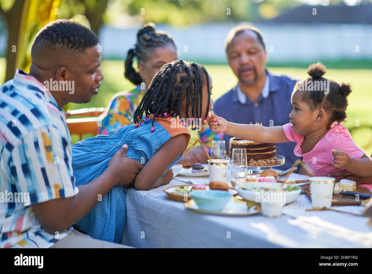 Famiglia multigenerazionale che festeggia il compleanno al tavolo del patio Foto Stock