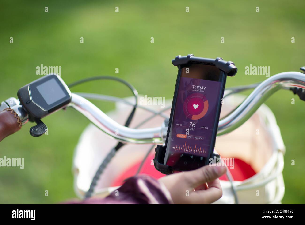 Donna POV in bicicletta che controlla la frequenza cardiaca con l'app per smartphone Foto Stock