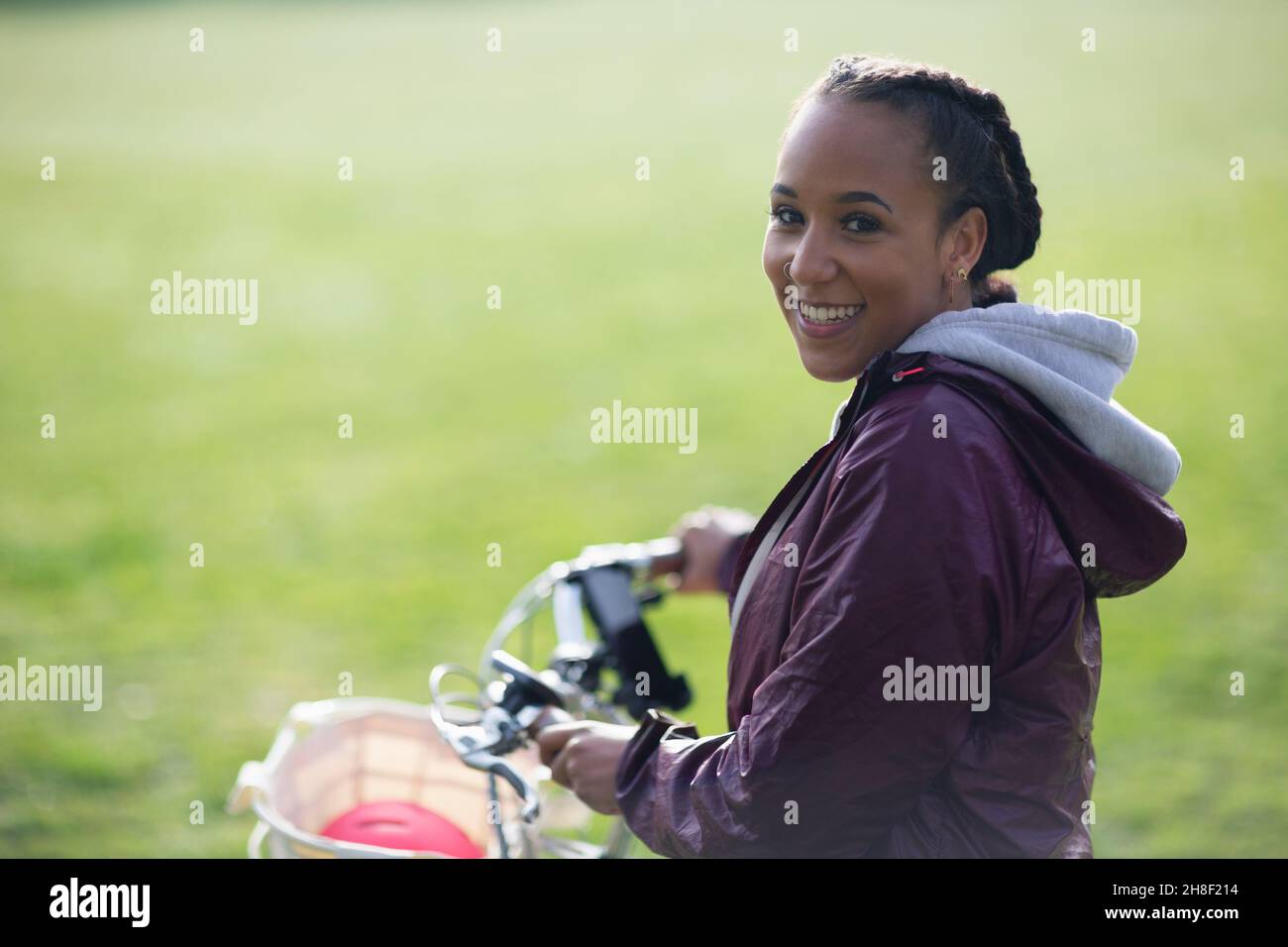Ritratto felice bella giovane donna in bicicletta nel parco Foto Stock
