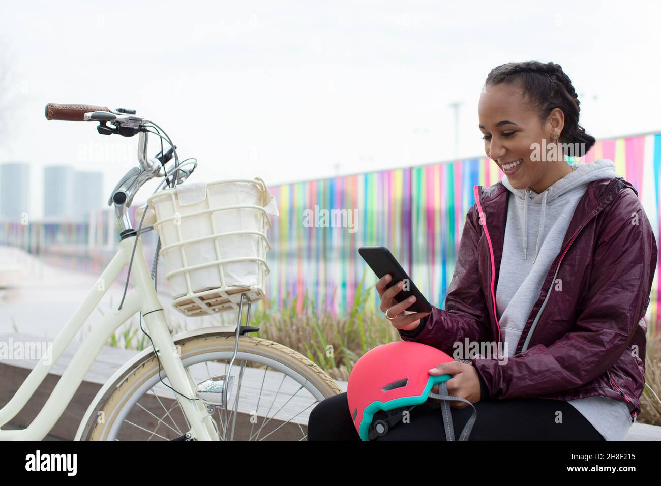 Ragazza adolescente felice con la bicicletta usando lo smart phone Foto Stock