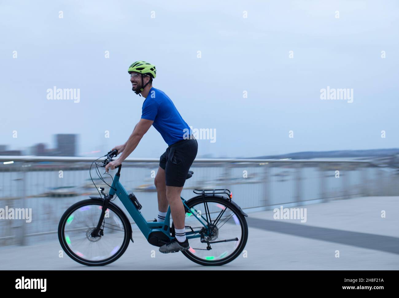Uomo in bicicletta lungo il lungomare urbano Foto Stock
