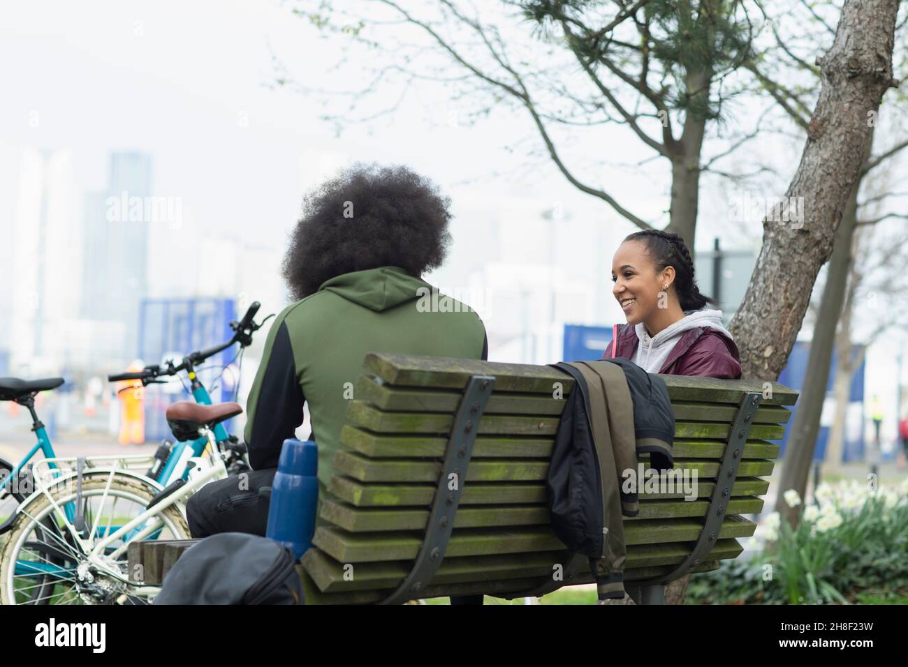 Amici adolescenti che parlano sul banco del parco Foto Stock