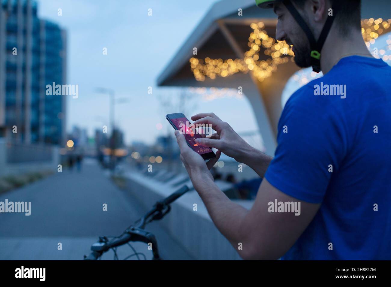 Uomo in bicicletta che guarda la frequenza cardiaca sull'app per smartphone in città Foto Stock