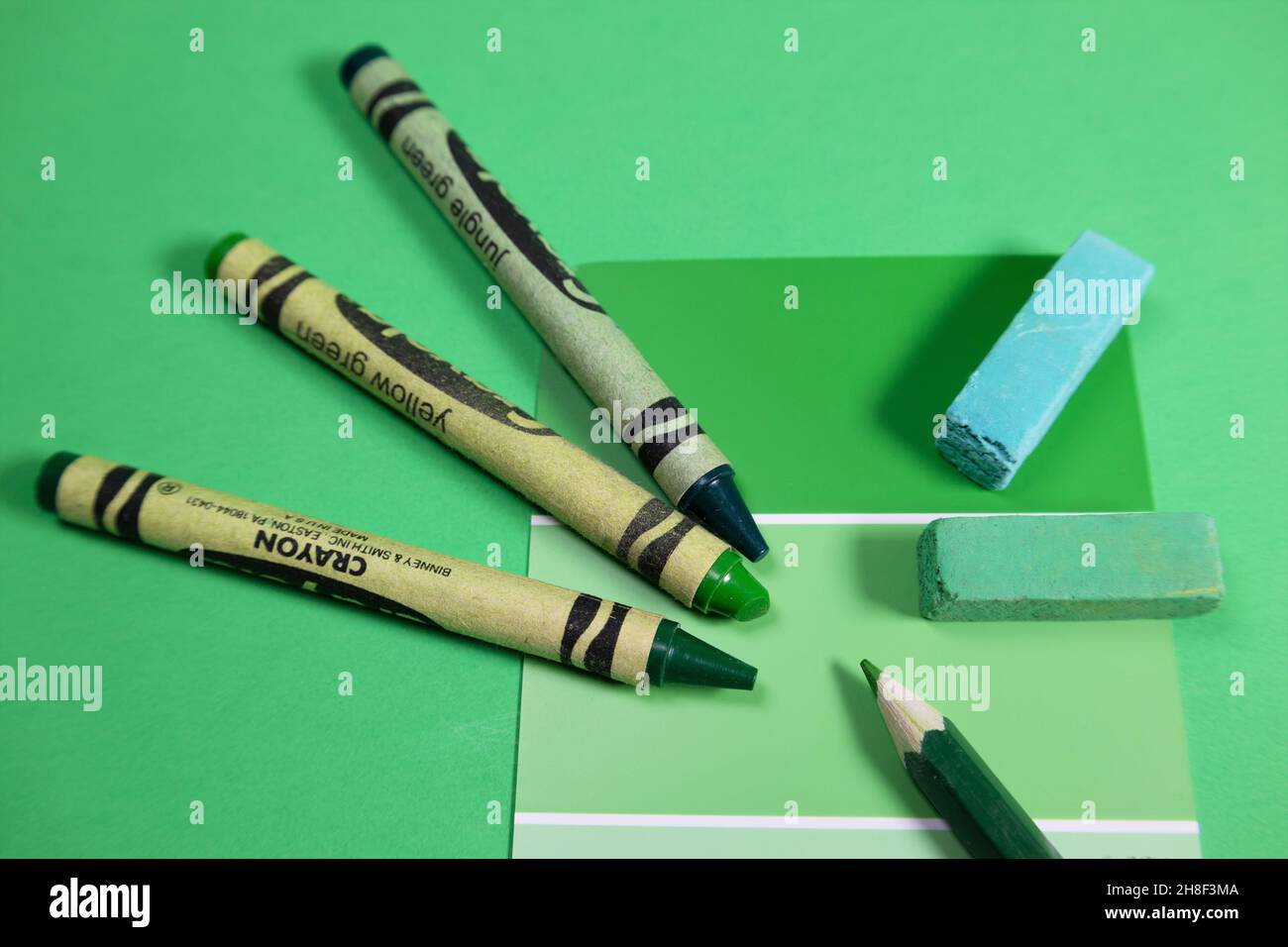 Un campione di vernice, pastelli, pastelli e matita colorata, tutti che rappresentano varie sfumature di verde. Foto Stock