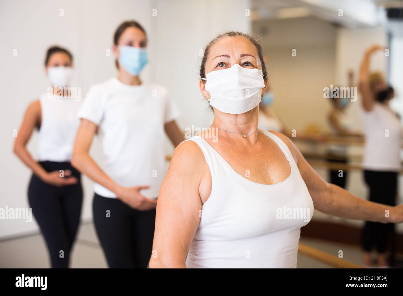 Gruppo di ballerini multietnici femminili che si allenano in maschere durante la pandemia COVID-19 Foto Stock