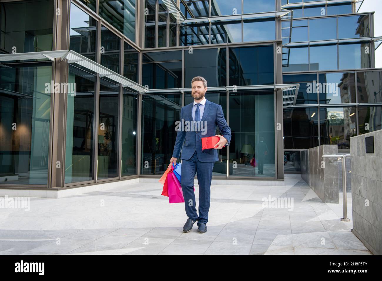 felice uomo d'affari a piedi con shopping bag presenta all'aperto a tutta lunghezza, closeout. Foto Stock