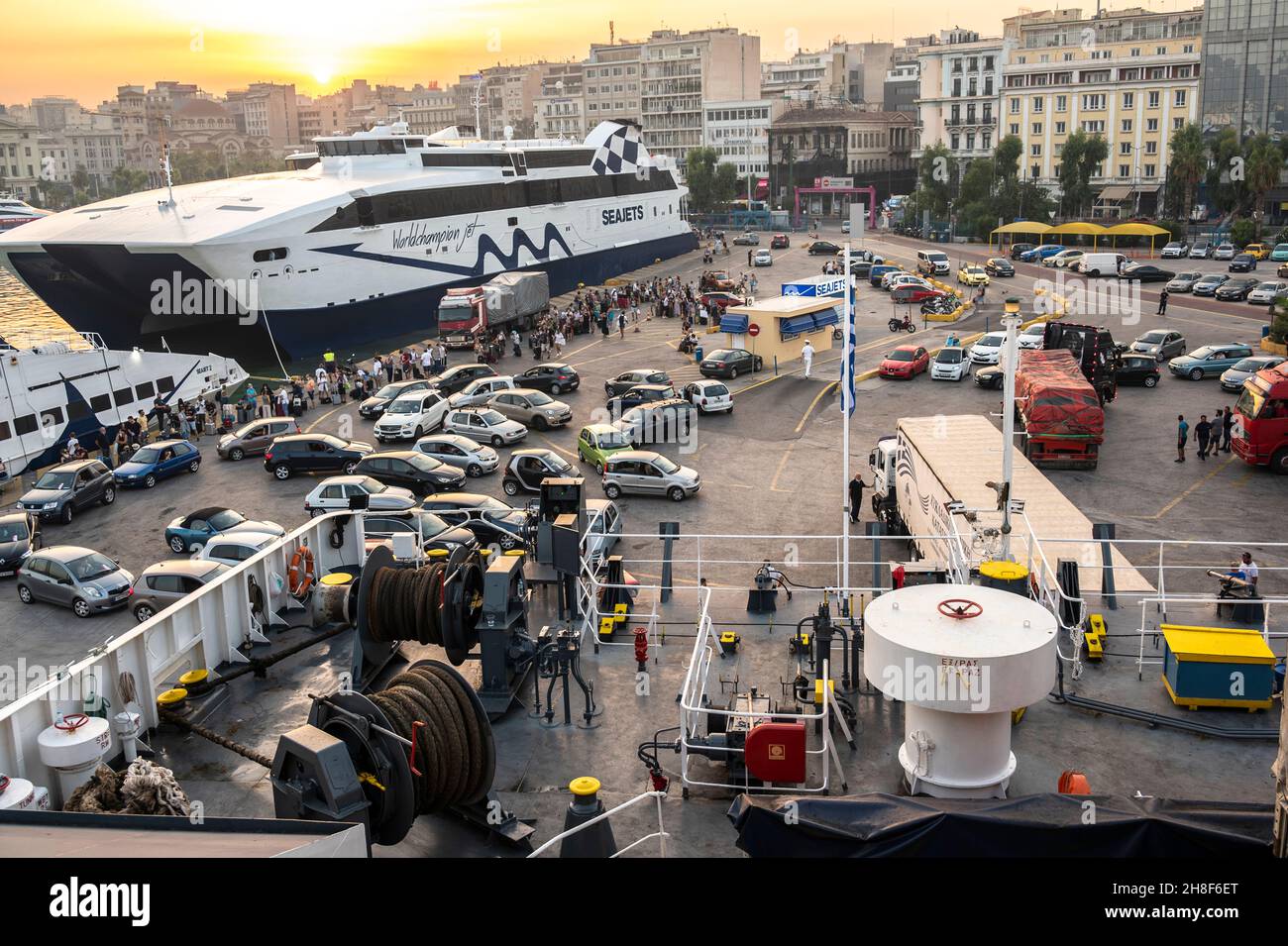 I passeggeri e i veicoli aspettano di salire a bordo del traghetto al porto del Pireo in Grecia Foto Stock