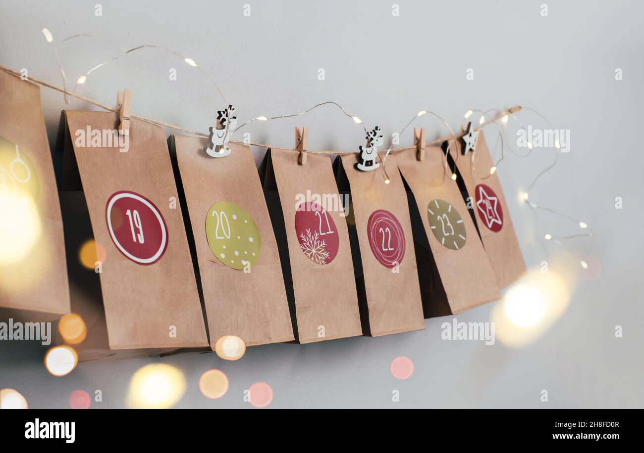 Calendario dell'avvento di Natale sospeso sul muro. Borse artigianali fatte a mano con regali e compiti per i bambini. Conto alla rovescia per la vigilia di Natale, in attesa del miracolo Foto Stock