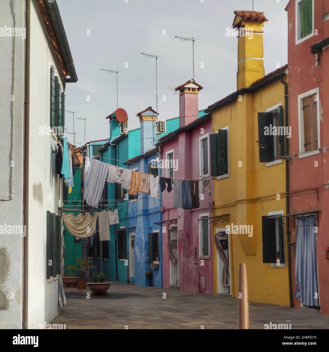 Tipica stradina con abiti appesi tra i colorati edifici di Burano Foto Stock