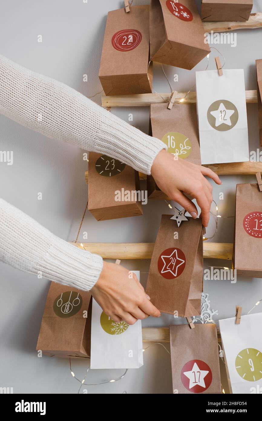 Calendario dell'avvento di Natale sospeso sul muro. Borse artigianali fatte a mano con regali e compiti per i bambini. Conto alla rovescia per la vigilia di Natale, in attesa del miracolo Foto Stock
