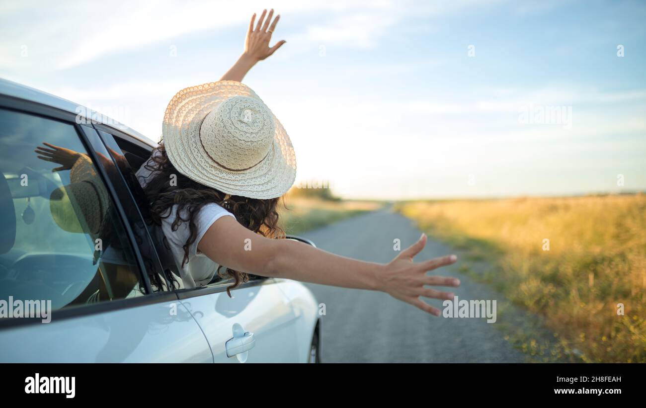 Ragazza con cappello che le braccia si attacca da un finestrino auto. Libertà e concetto di avventura. Foto Stock