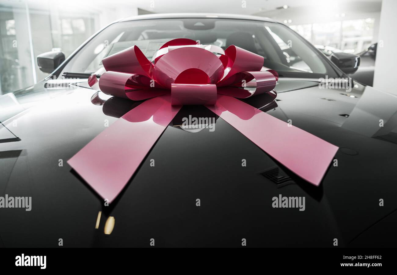 Vendite auto. Vettura elegante nuova di zecca con grande bow rosa regalo. Perfetto presente nel settore automobilistico. Foto Stock