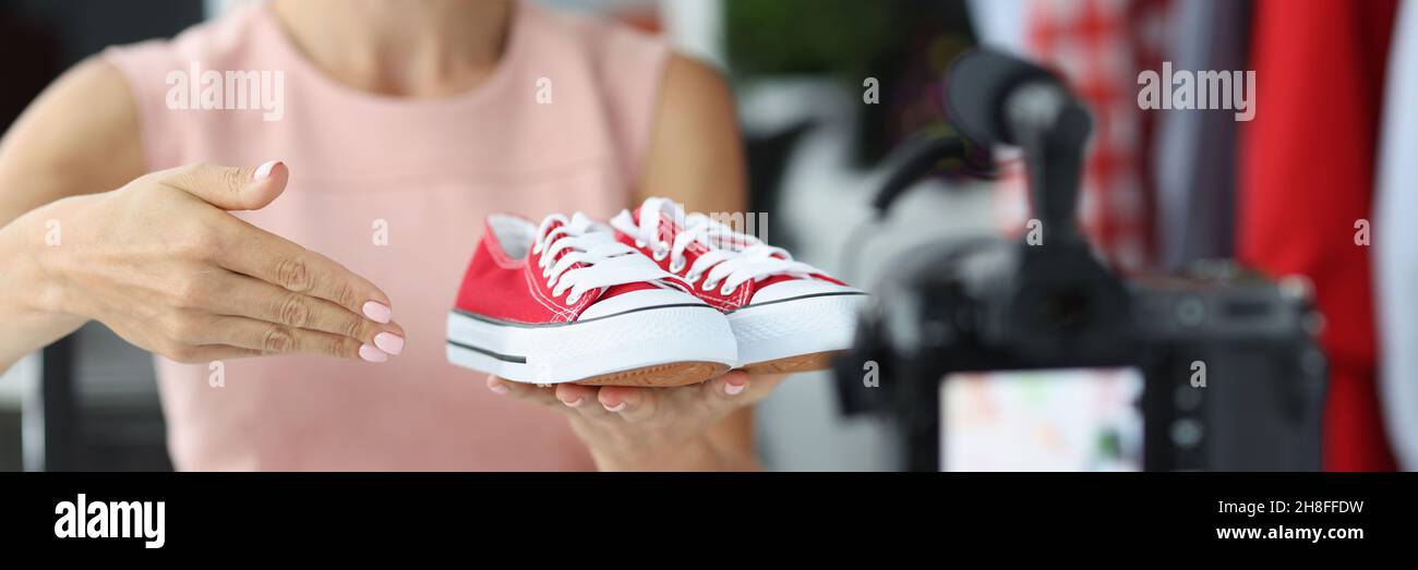 Donna venditore consulente mostra a macchina fotografica scarpe sportive rosse Foto Stock