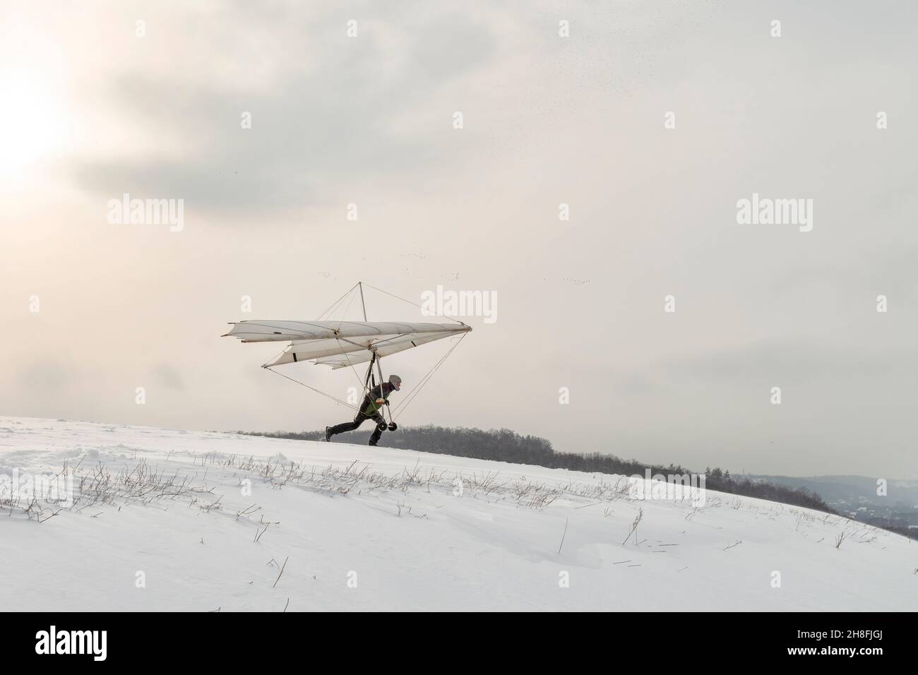 Il pilota di deltaplano corre velocemente in pendenza. Sogno di volare si avveri. Imparare sport estremo. Attività rischiosa Foto Stock