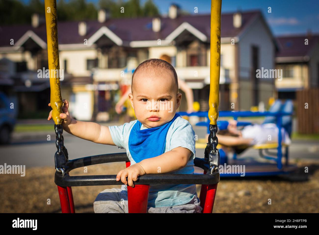 Carino felice sorridente bambino che oscilla al parco giochi all'aperto Foto Stock