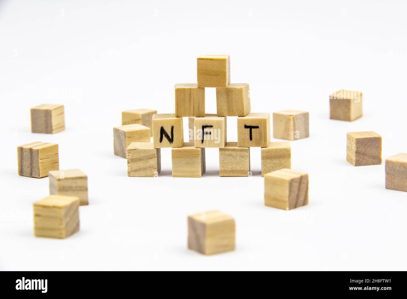 Parola NFT (token non fungibile) scritta sui cubi di legno su sfondo bianco. Token non-fungibili Concept NFT. Foto Stock