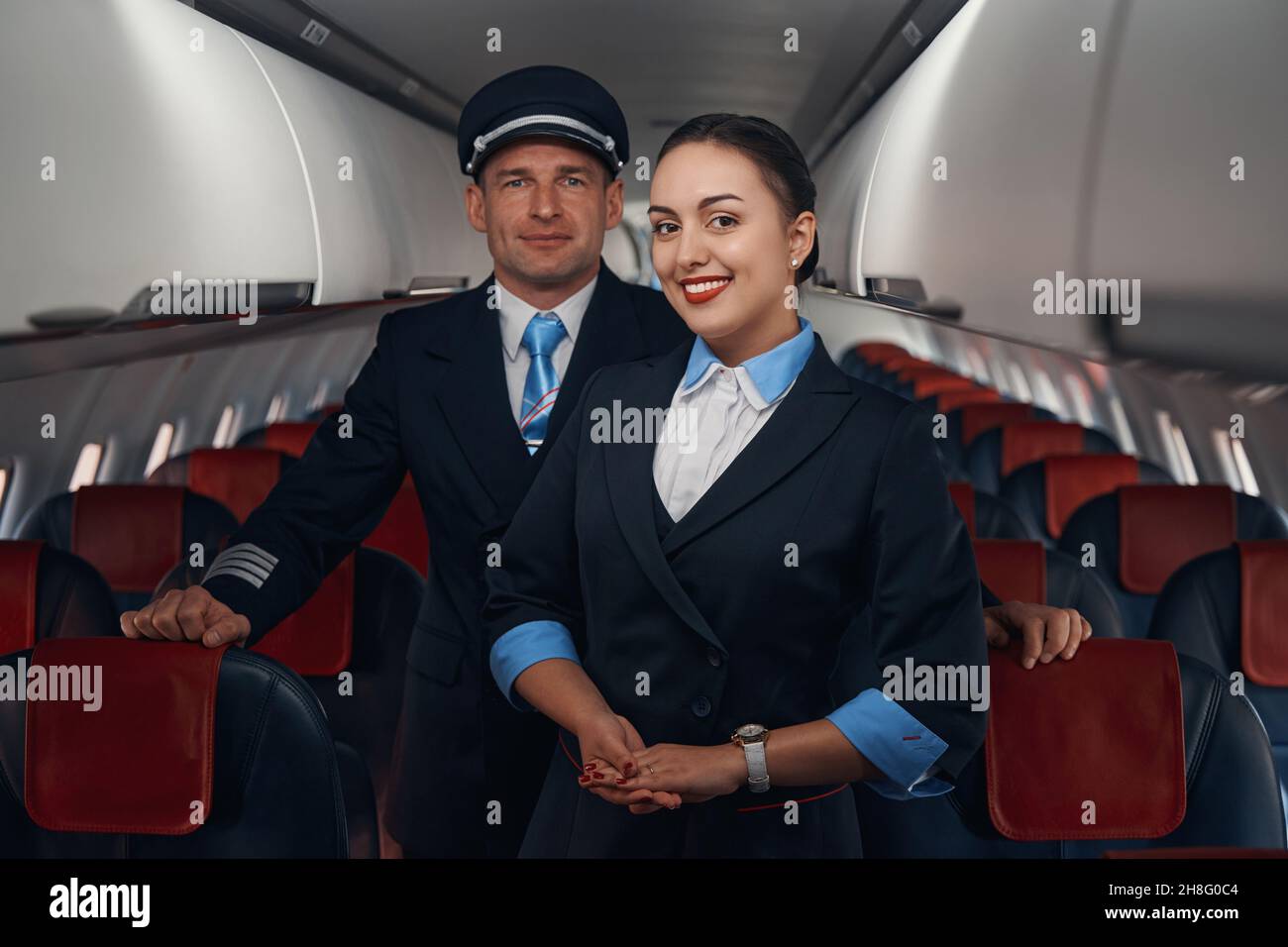 Sorridente hostess e capitano in piedi sul corridoio Foto Stock