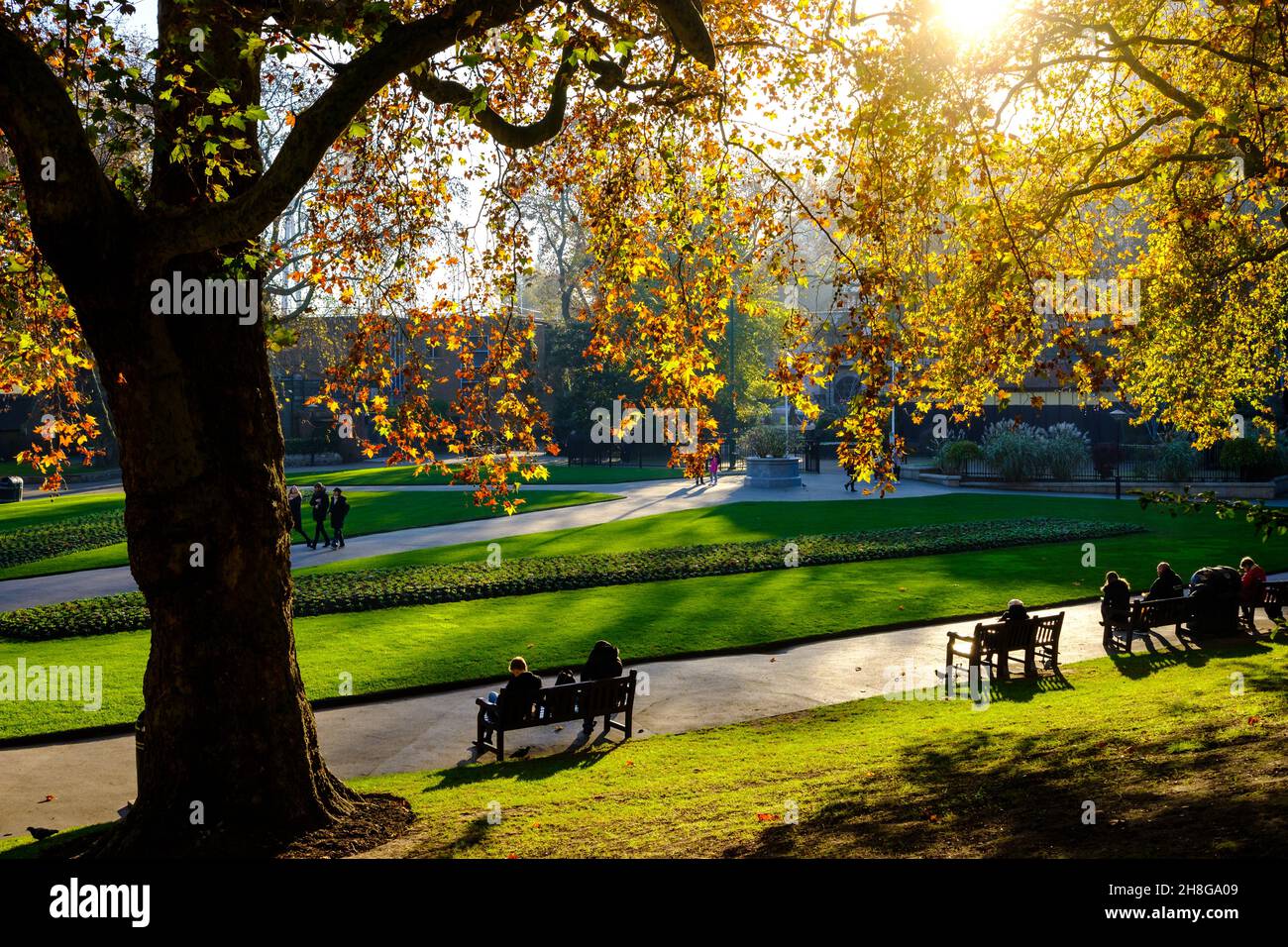 La gente si siede sulle panchine in Victoria Embankment Gardens Foto Stock