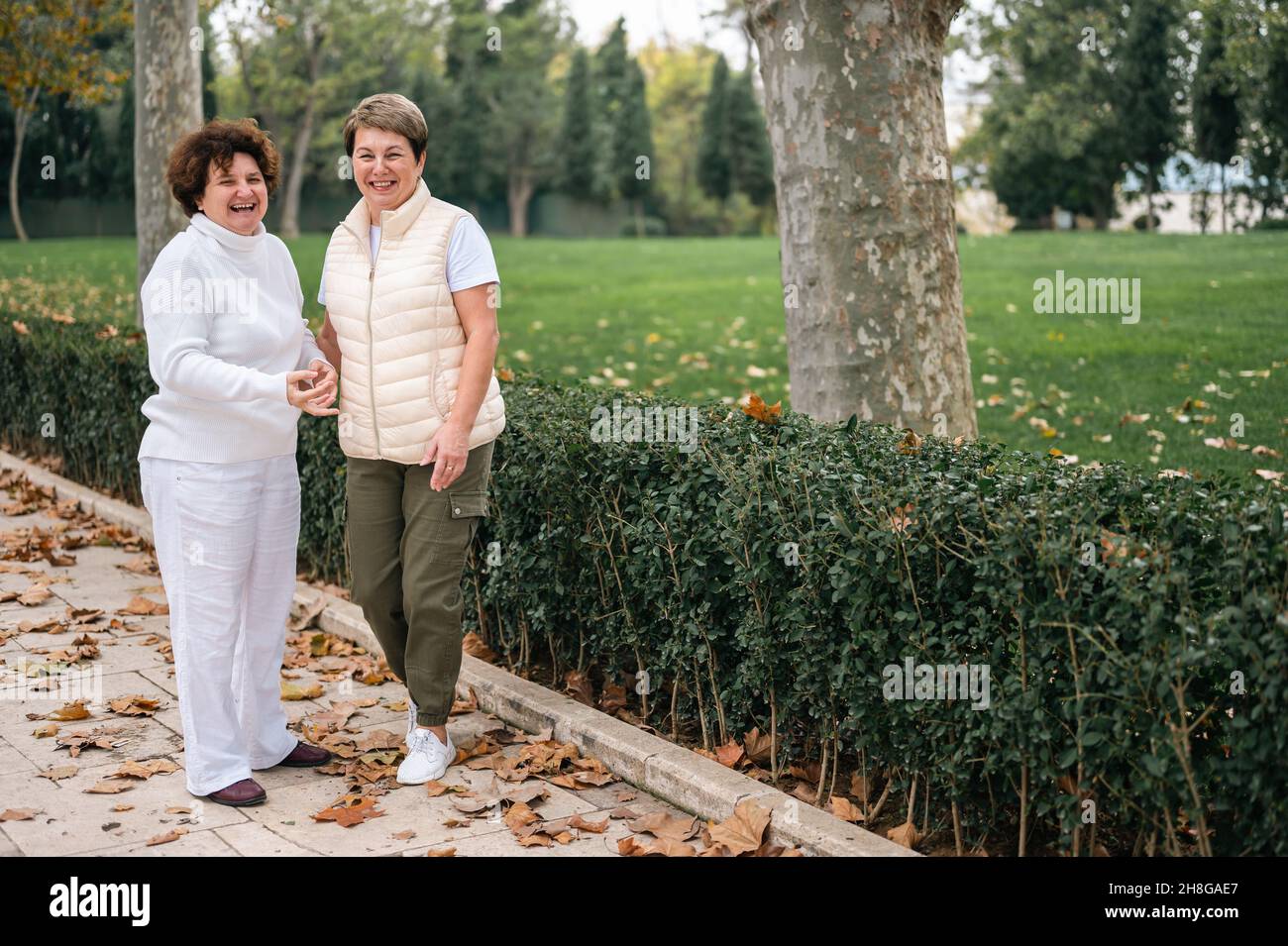 due donne anziane ridono e guardano la macchina fotografica. due vecchi amici si sono incontrati nel parco. stile di vita attivo di donne anziane e di mezza età. amici anziani ar Foto Stock