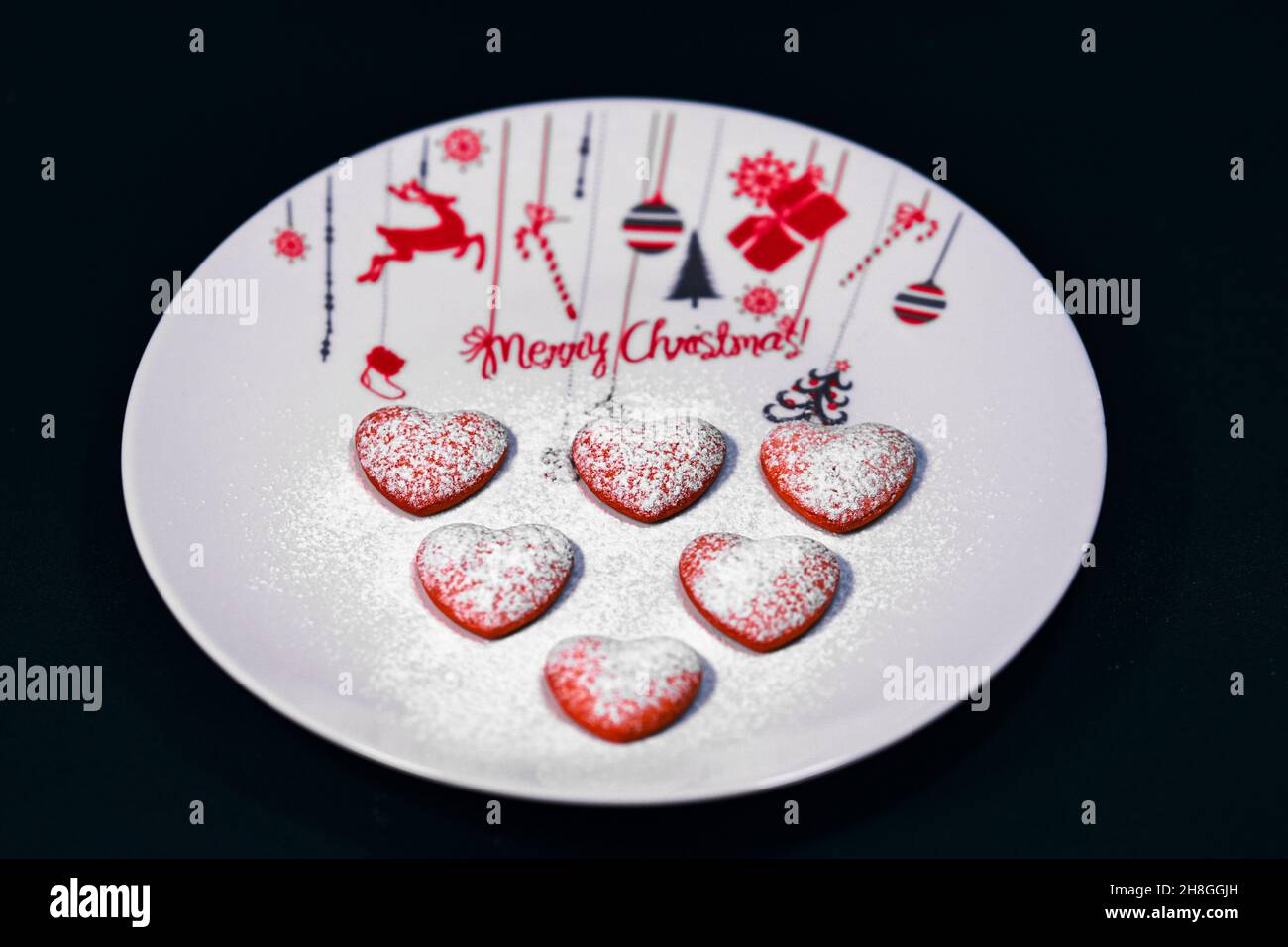 Biscotti a forma di cuore sul piatto a tema natalizio Foto Stock