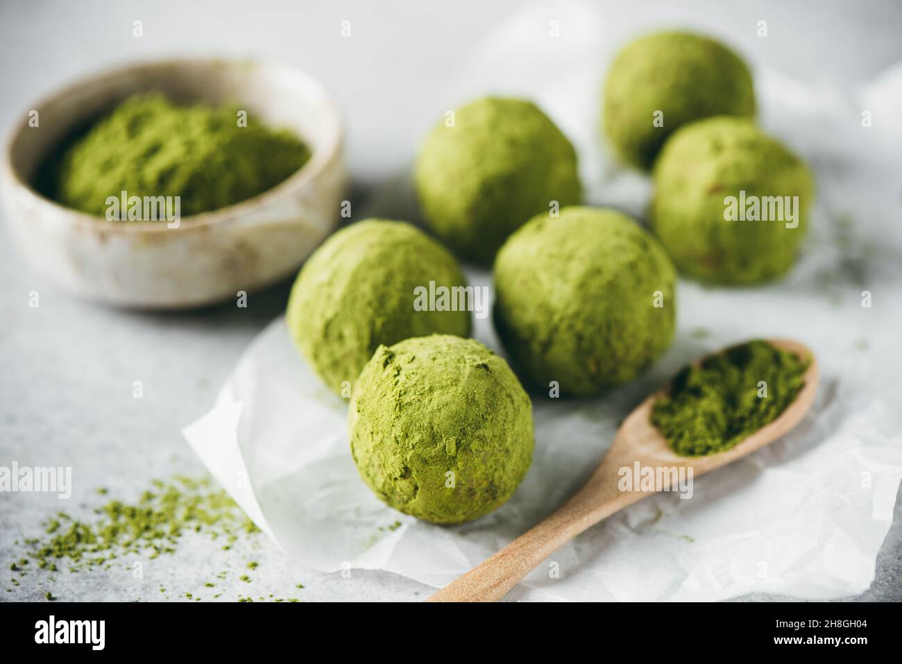 Palle di energia matcha tè verde su carta pergamena, primo piano vista. Tartufi vegani superalimentari sani Foto Stock