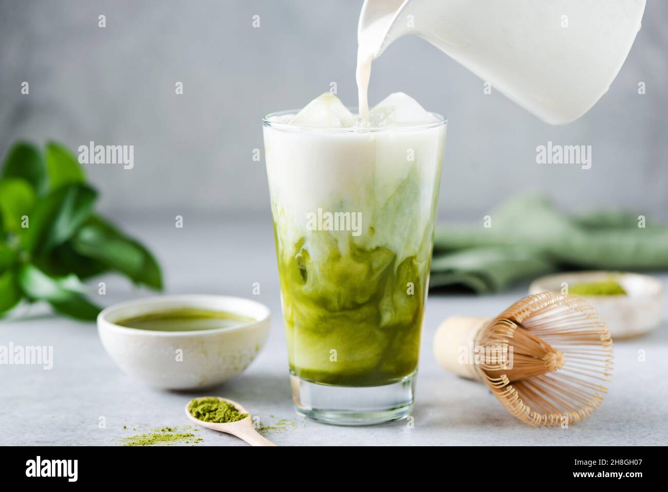 Latte di soia versato in tè ghiaccio matcha. Bevanda vegana sana Foto Stock