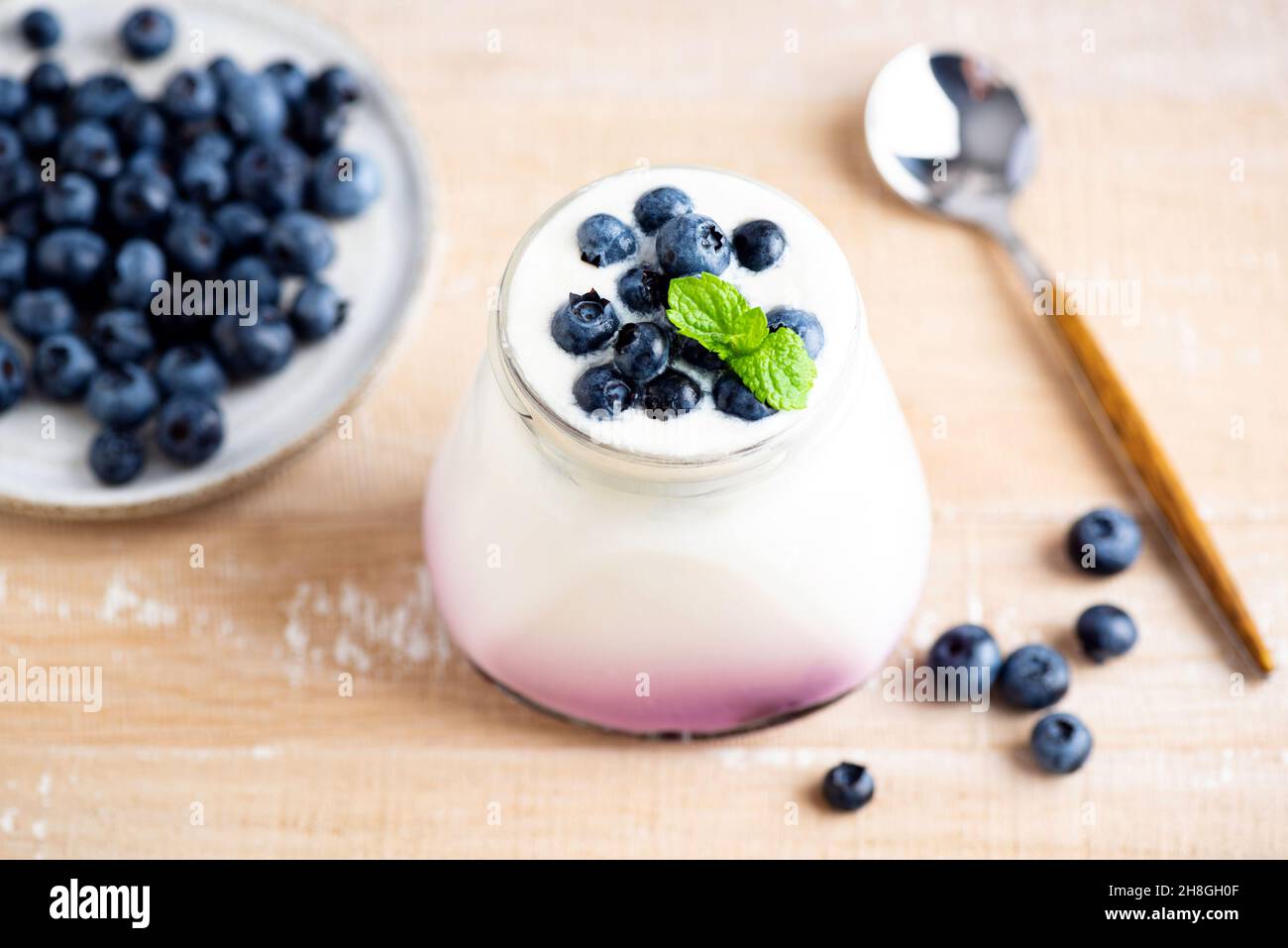 Yogurt al mirtillo in vaso su tavola di legno. Un sano latticino ricco di calcio e vitamine Foto Stock