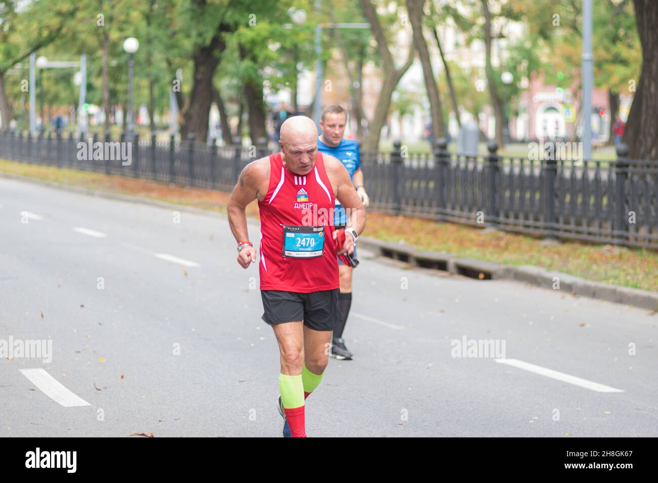 DNIPRO, UCRAINA - 26 SETTEMBRE 2021: Uomo anziano duro che corre su una strada vuota della città durante 21 km di distanza di Almaz gruppo Dnipro Marathon corsa Foto Stock