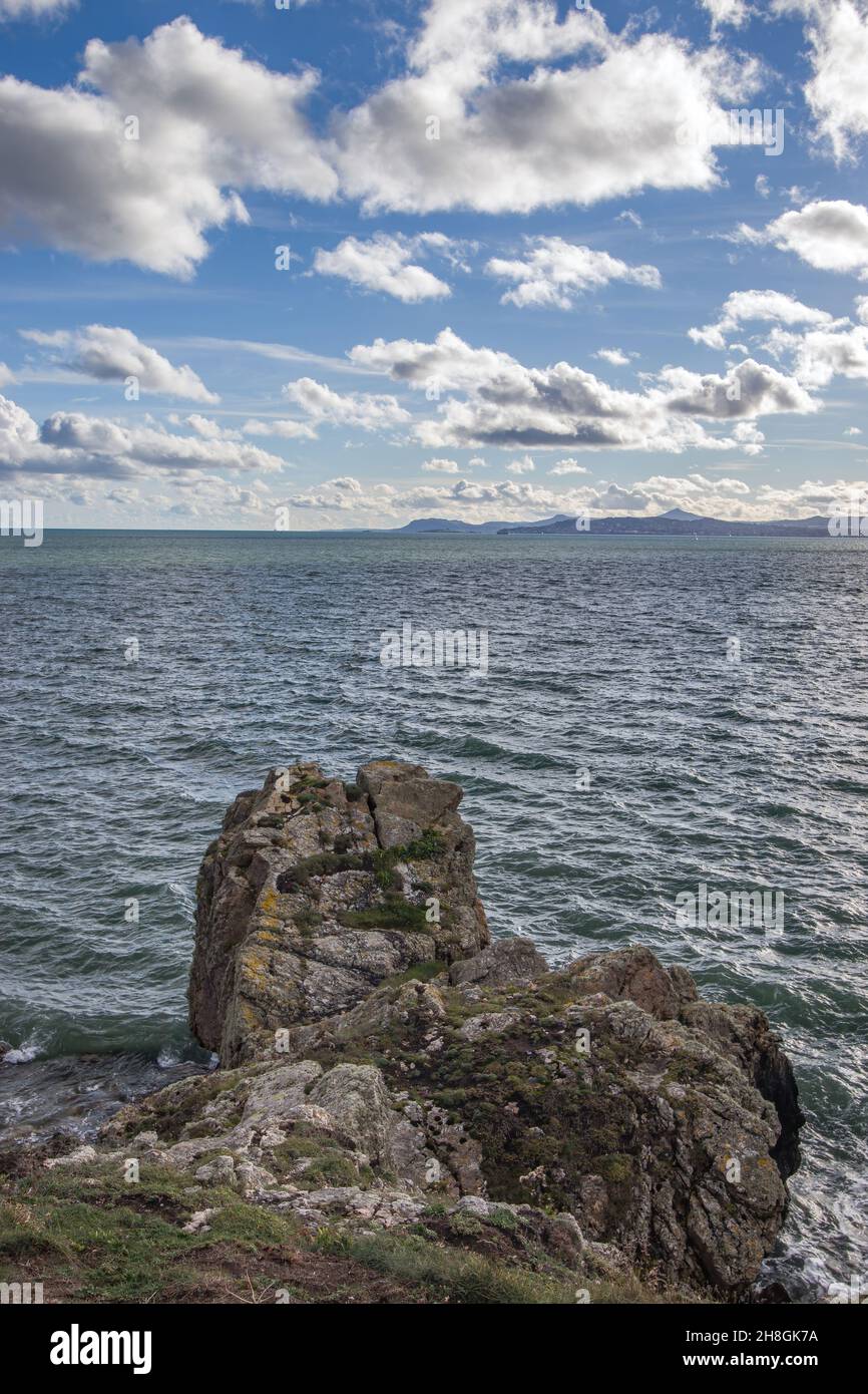 La penisola di Howth Head in giornata soleggiata e nuvolosa, baia nascosta, cielo drammatico, contea di Dublino, Seashore di scogliere, Baie e rocce paesaggio, Irlanda Foto Stock