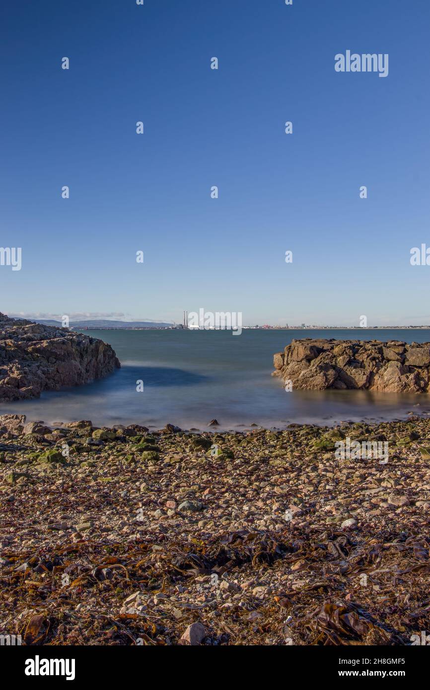 La penisola di Howth Head in giornata soleggiata e nuvolosa, esposizione a lungo, Dublino County, Seashore di scogliere, baie e rocce paesaggio, Irlanda Foto Stock