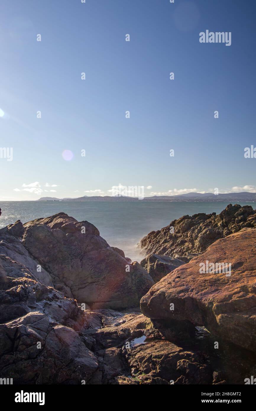 La penisola di Howth Head in giornata soleggiata e nuvolosa, esposizione a lungo, Dublino County, Seashore di scogliere, baie e rocce paesaggio, Irlanda Foto Stock