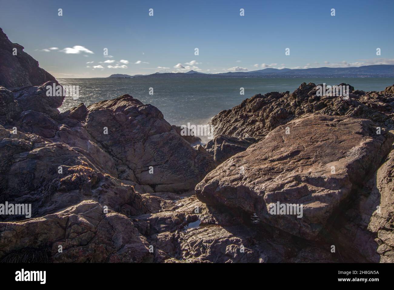 La penisola di Howth Head in giornata soleggiata e nuvolosa, esposizione a lungo, Dublino County, Seashore di scogliere, baie e rocce paesaggio, Irlanda Foto Stock