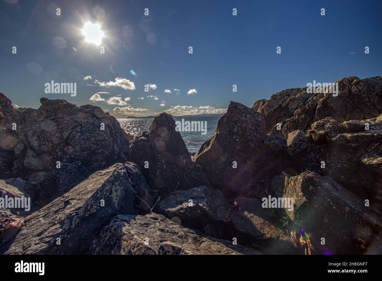 La penisola di Howth Head in giornata soleggiata e nuvolosa, esposizione a lungo, Dublino County, Seashore di scogliere, baie e rocce paesaggio, Irlanda Foto Stock