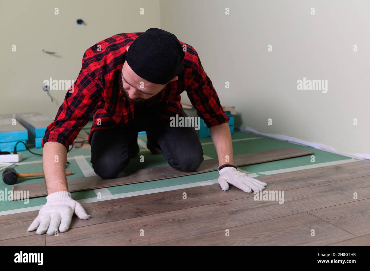 Lavora uomo installa laminato. Riparazione dell'appartamento, posa di pavimenti in laminato Foto Stock
