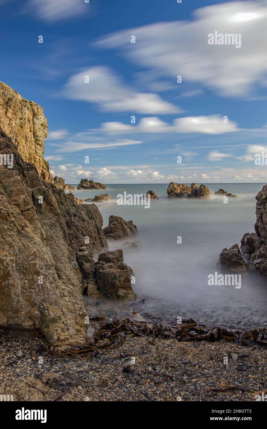 La penisola di Howth Head in giornata soleggiata e nuvolosa, esposizione a lungo, Dublino County, Seashore di scogliere, baie e rocce paesaggio, Irlanda Foto Stock