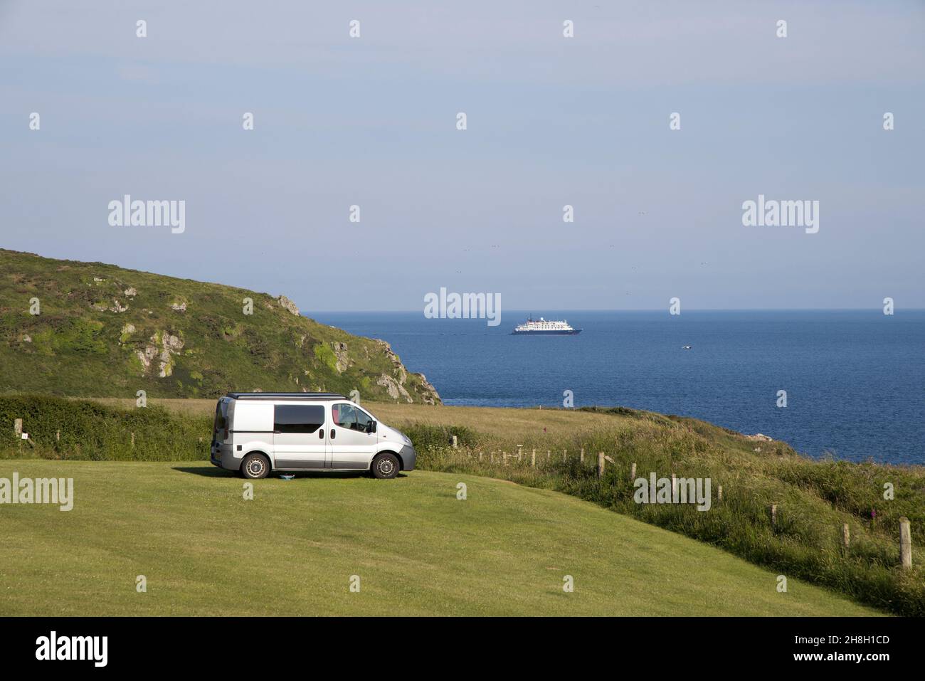 Camper in campo con traghetto in lontananza, Marloes, Galles occidentale, Regno Unito Foto Stock