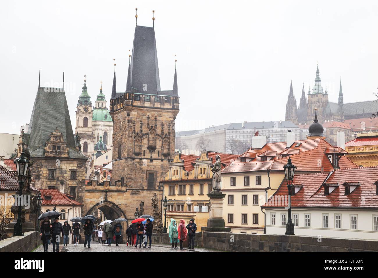 Praga - 11 marzo 2020: Ponte Carlo e Castello di Praga. Le persone con ombrelloni camminano sotto la pioggia sul Ponte Carlo Foto Stock