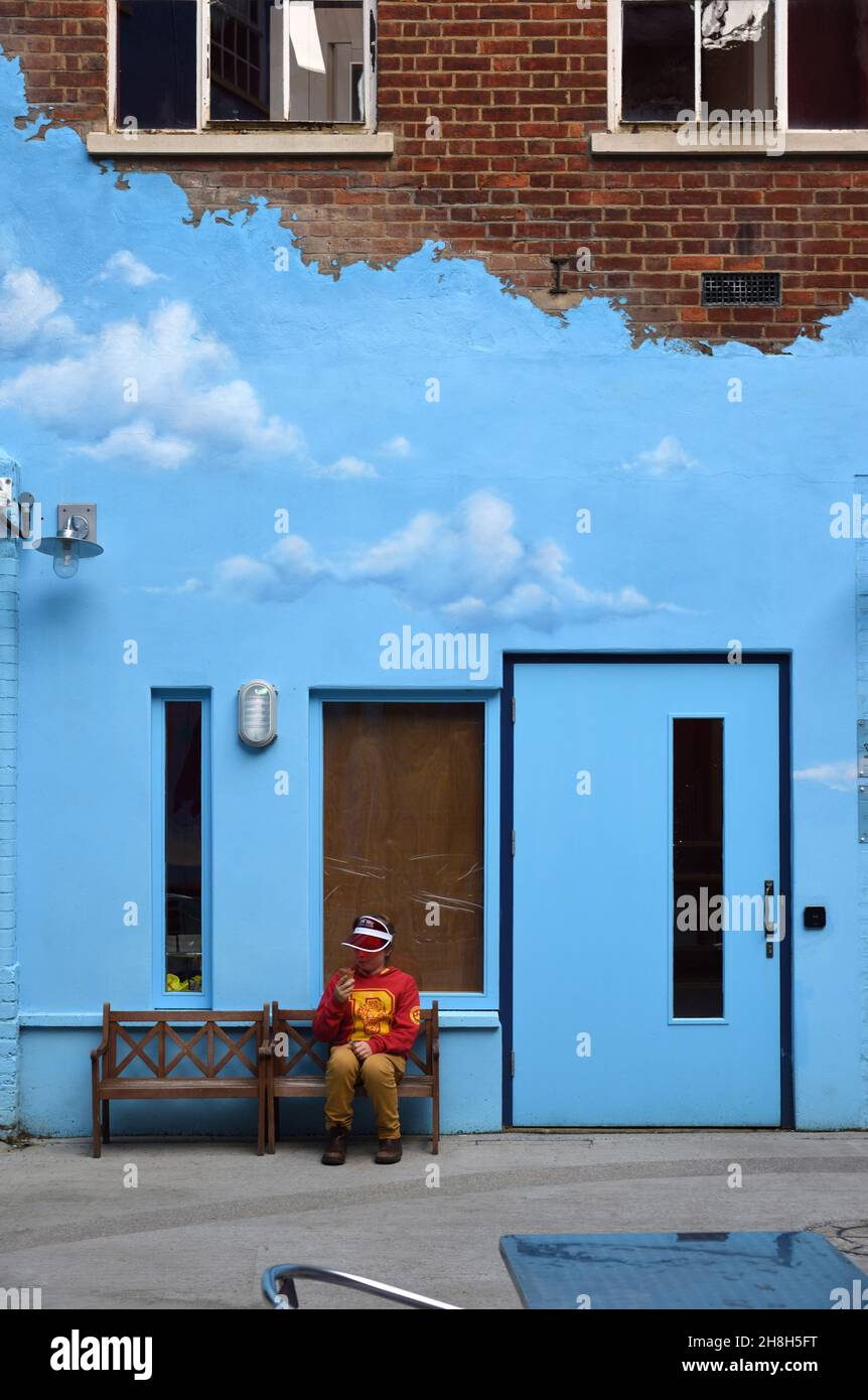 Ragazzo seduto sulla panchina di fronte alla facciata blu, Blue Wall e Blue Door nel museo di storia Oxford Inghilterra Foto Stock