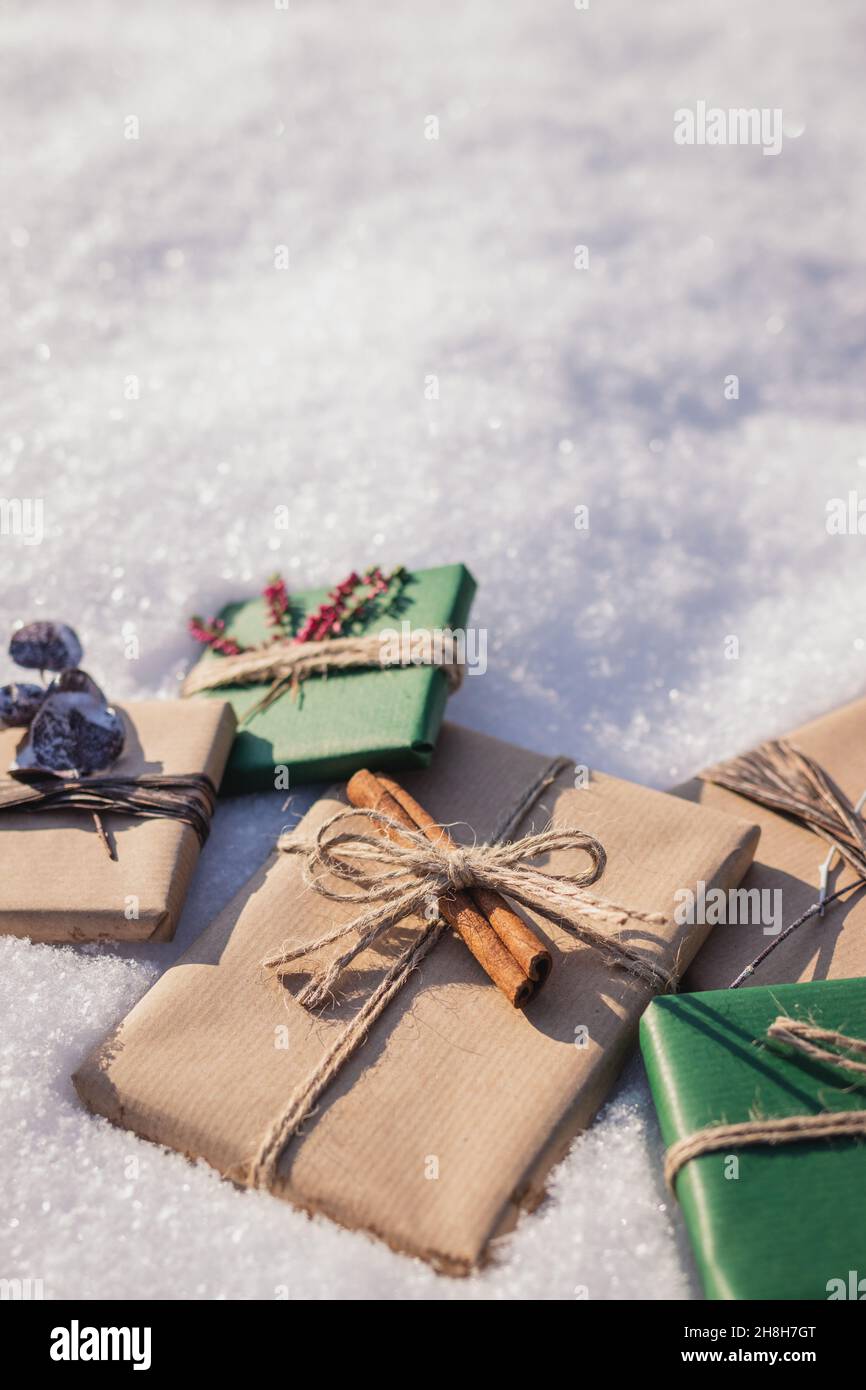 Avvolti regali di Natale con decorazione in neve. Confezioni regalo in carta da imballaggio kraft verde e marrone Foto Stock