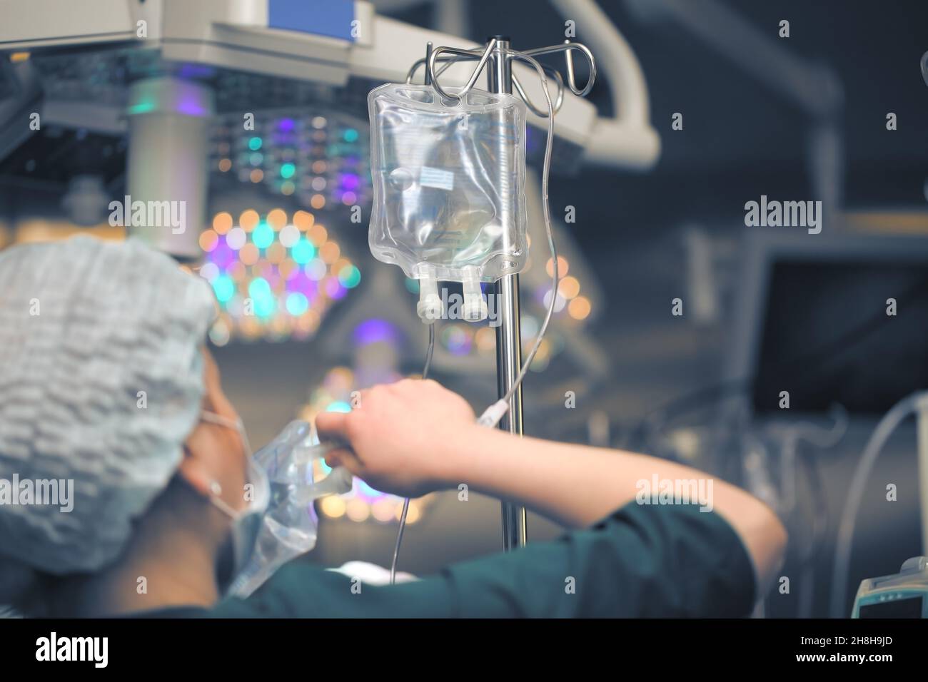 Infermiere donna che sostituisce i sacchetti di soluzione nel sistema di gocciolamento nella sala operatoria. Foto Stock