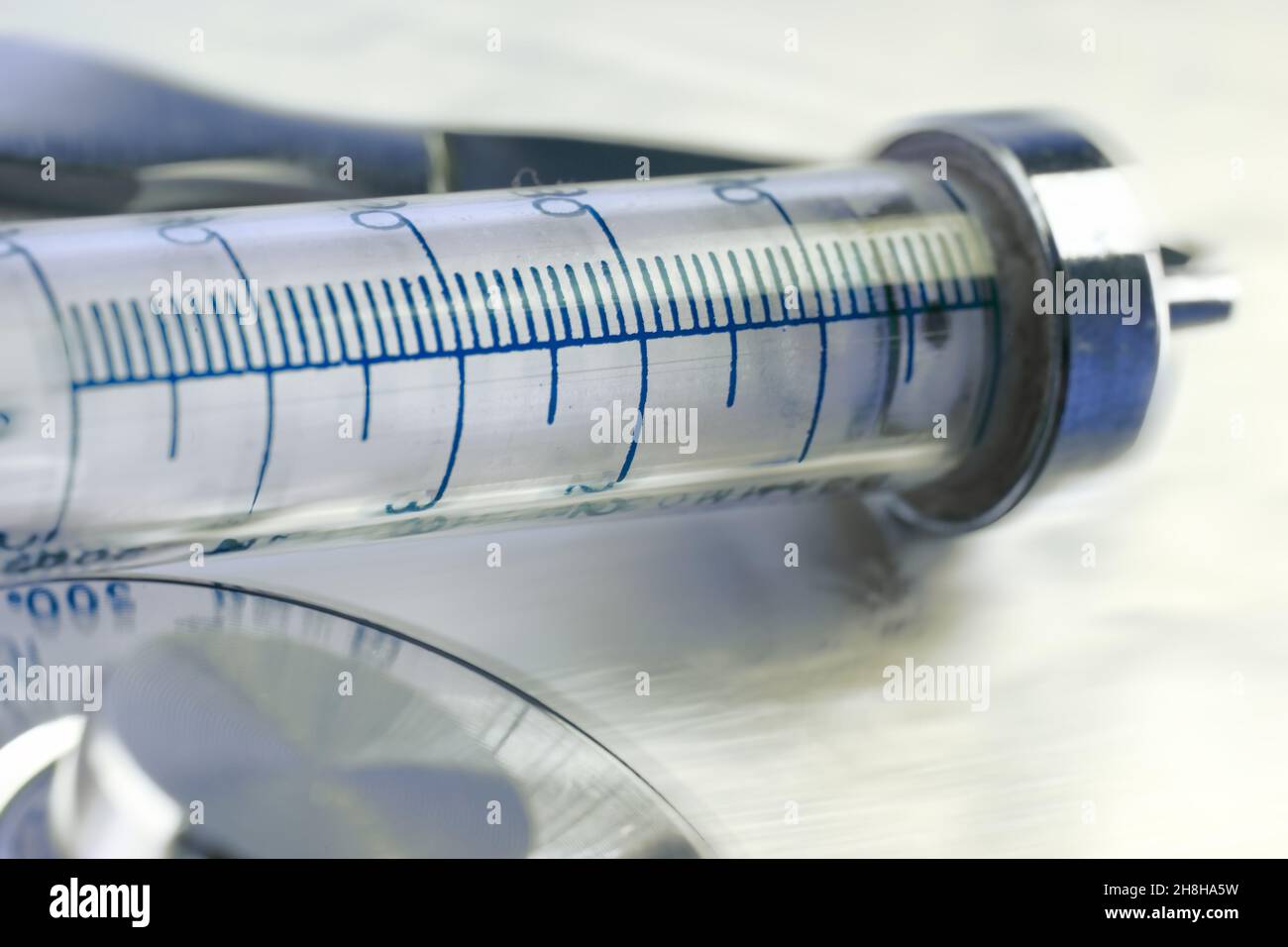 Vecchia siringa di vetro sulla superficie in acciaio lucido in primo piano. Foto Stock