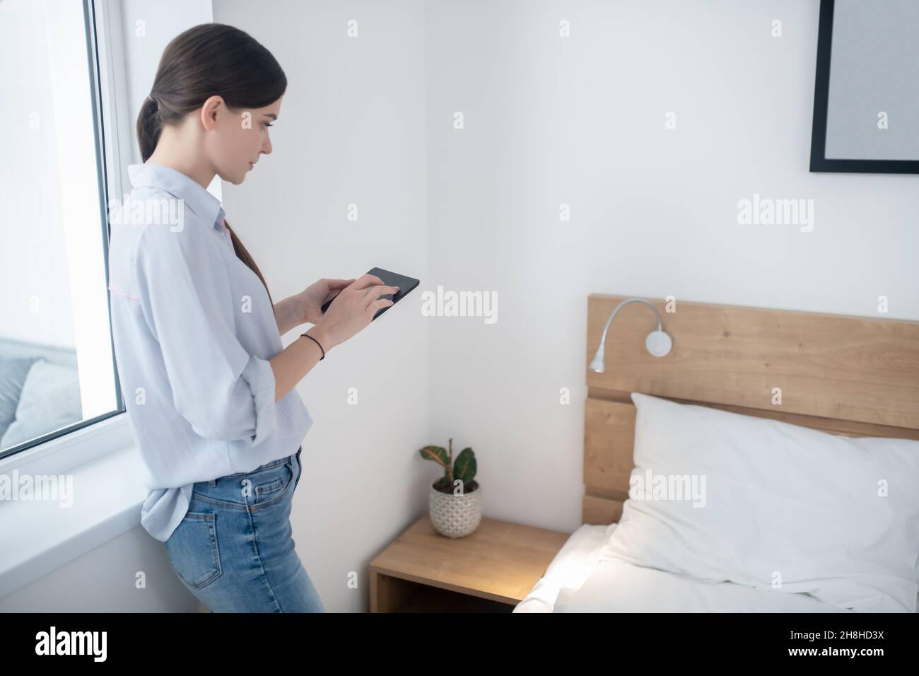 Femmina che controlla un telecomando in camera da letto Foto Stock