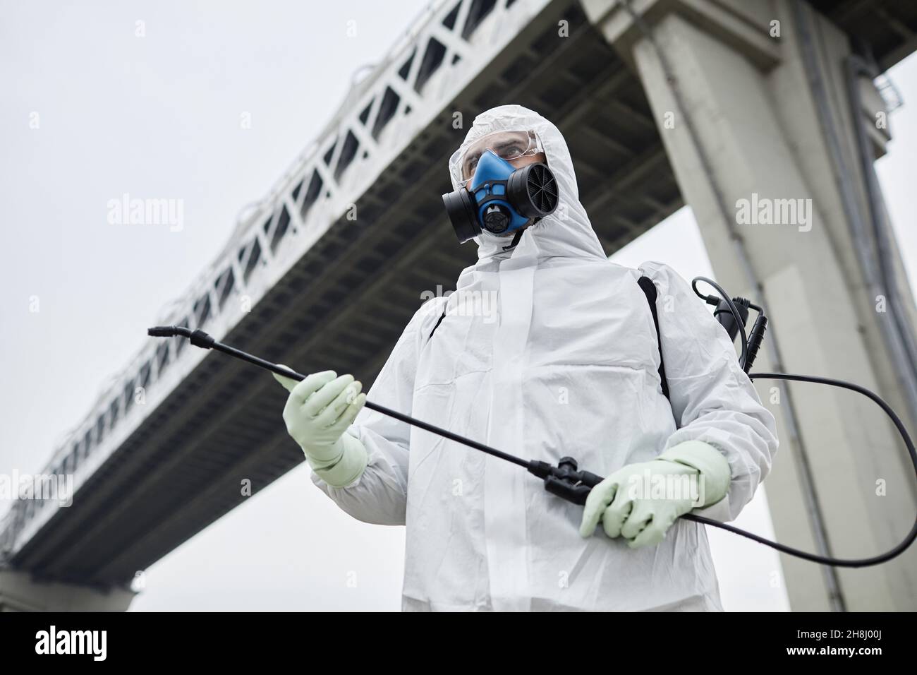 Ritratto industriale a basso angolo di uomo indossando tute in piedi sotto il ponte, spazio copia Foto Stock