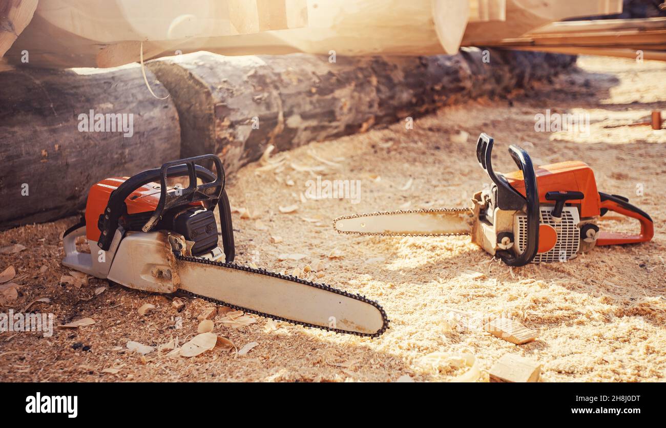 Banner concept segheria di tronchi, lumberjack. Primo piano due motoseghe si trovano sullo sfondo dei tronchi. Foto Stock