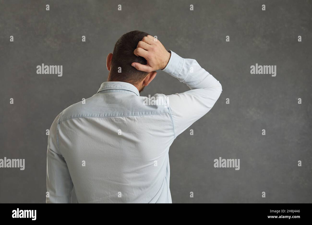 Vista posteriore di un uomo pensivo che graffia la testa Foto Stock