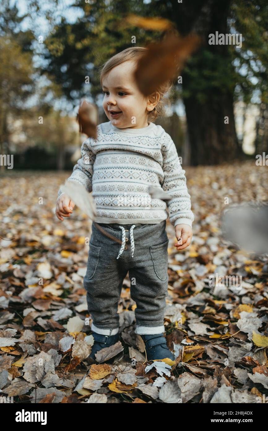 Adorabile ragazzo di un anno che cammina e gioca nel parco autunnale. Foto Stock