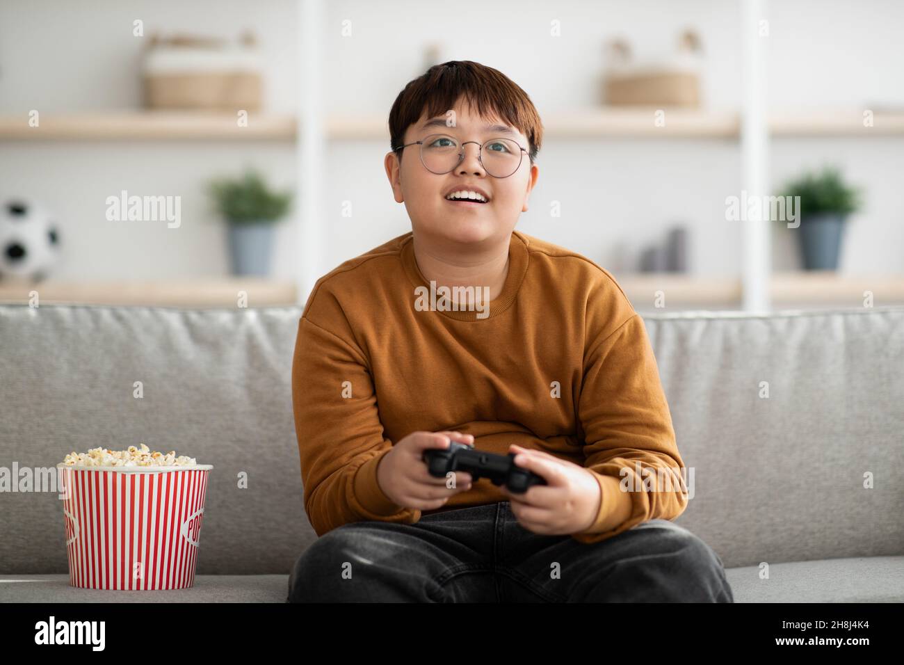 Ragazzo asiatico felice giocare a casa video gioco portatile Foto Stock